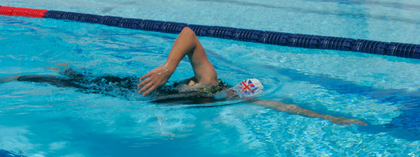 Person swimming front crawl stroke in open air pool